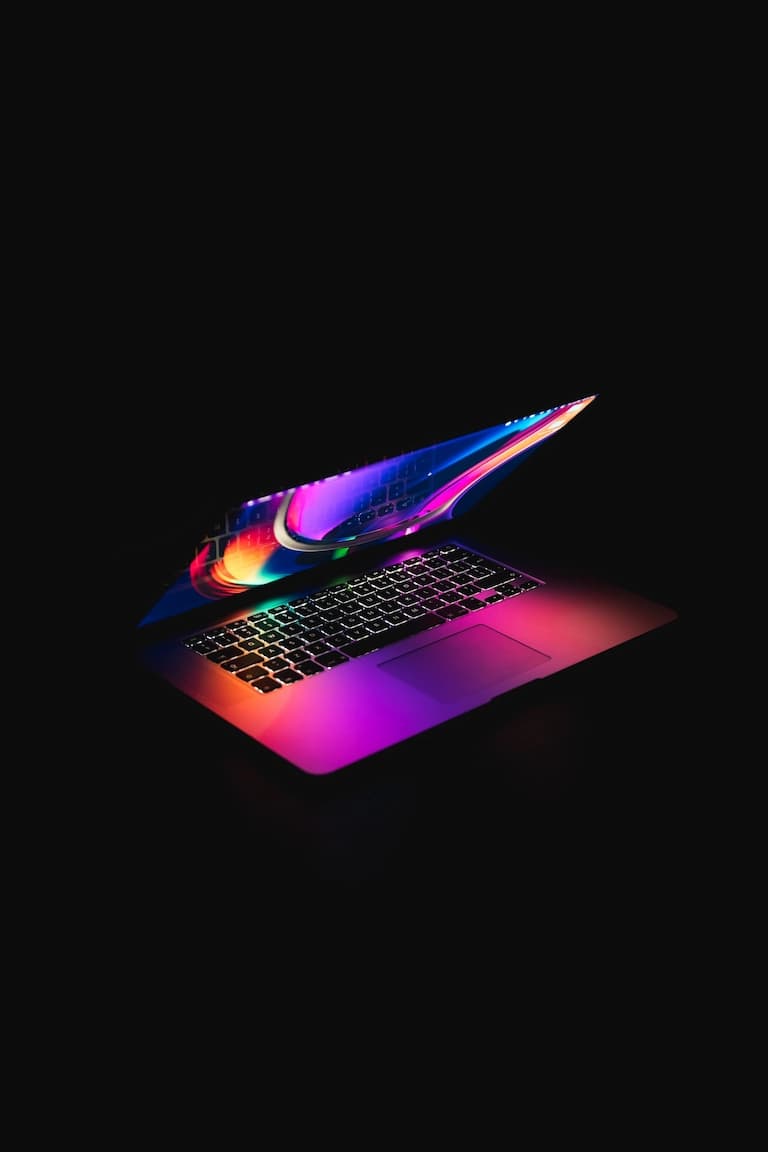 A smaller Mac laptop with neon purple and blue lights